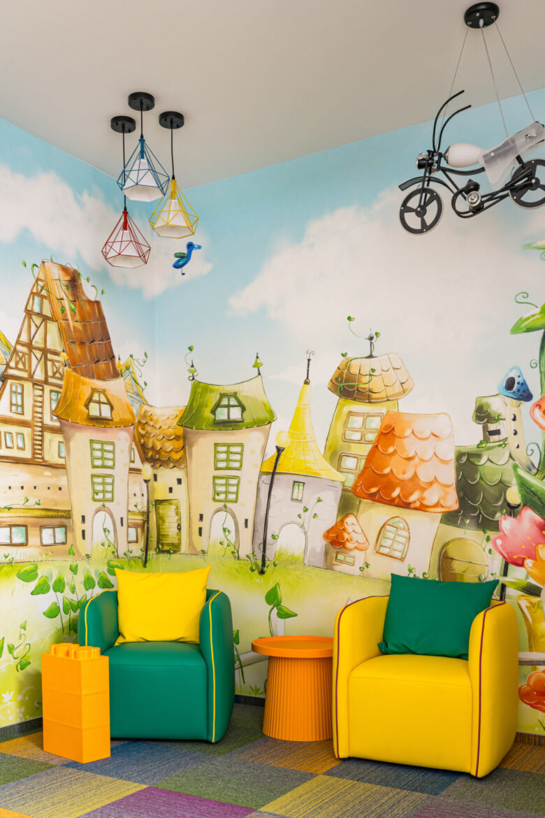 Seats and tables beside the play area, against an illustrated townscape.