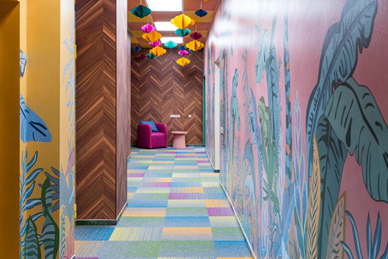 Circulation space with illustrated walls and suspended coloured elements.