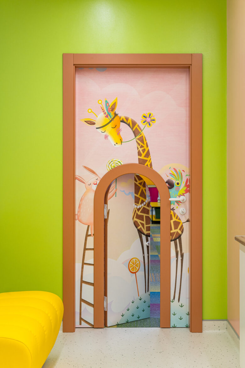 A small arched door set within a full-height treatment-room door.