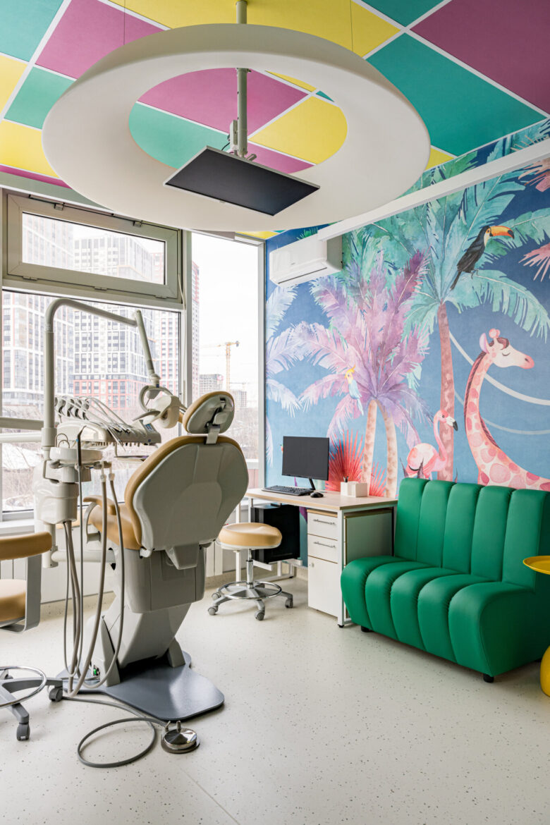 Treatment room with dental equipment, seating and an illustrated wall.